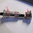 This illustrates the bottom bracket with the sleeves (shown by red arrows) which expand, when forced to slide to the ends of the bottom bracket, as the bottom bracket halves are screwed together
